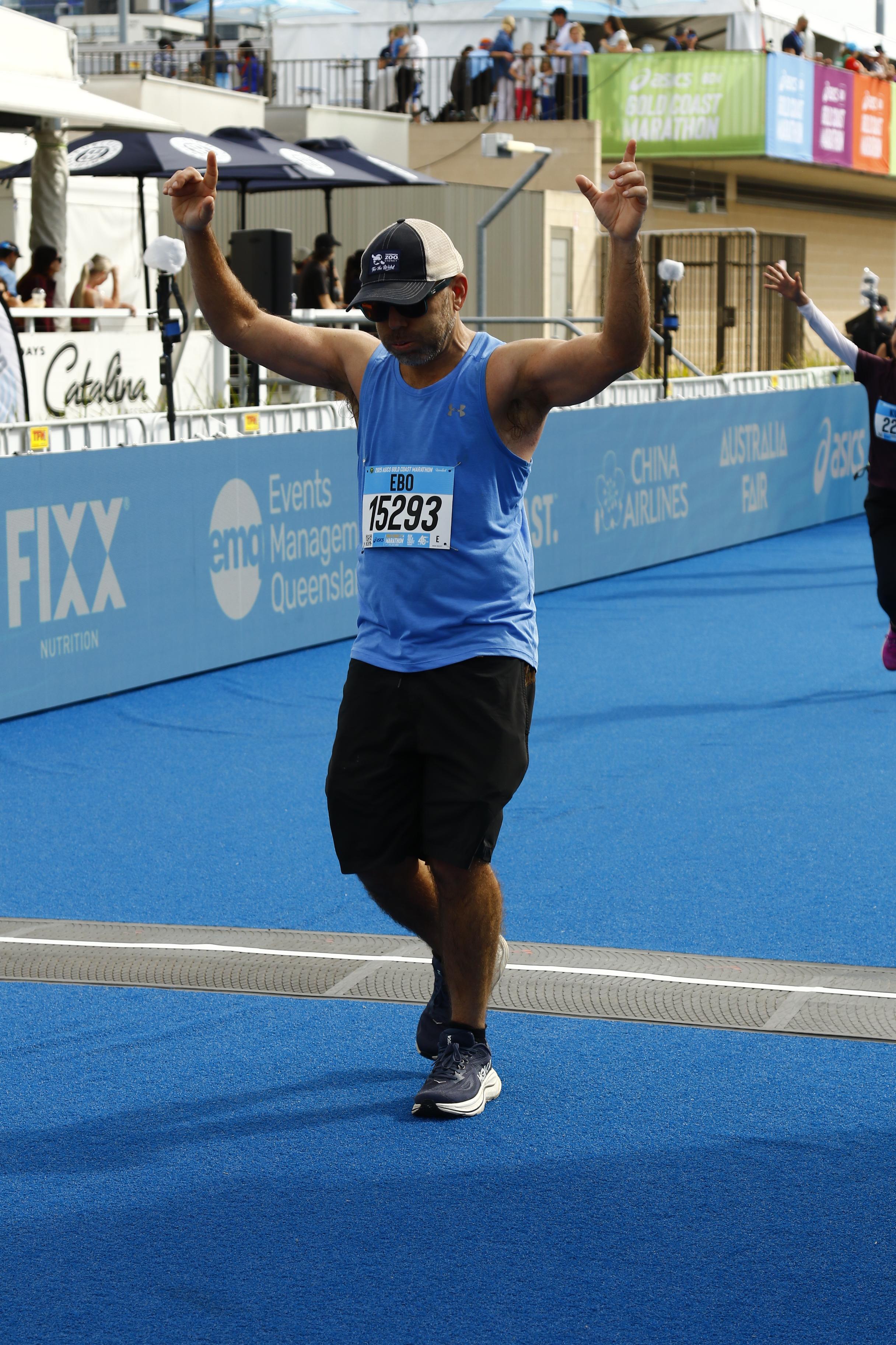 Eban crossing the finish line of a road race with both arms raised.