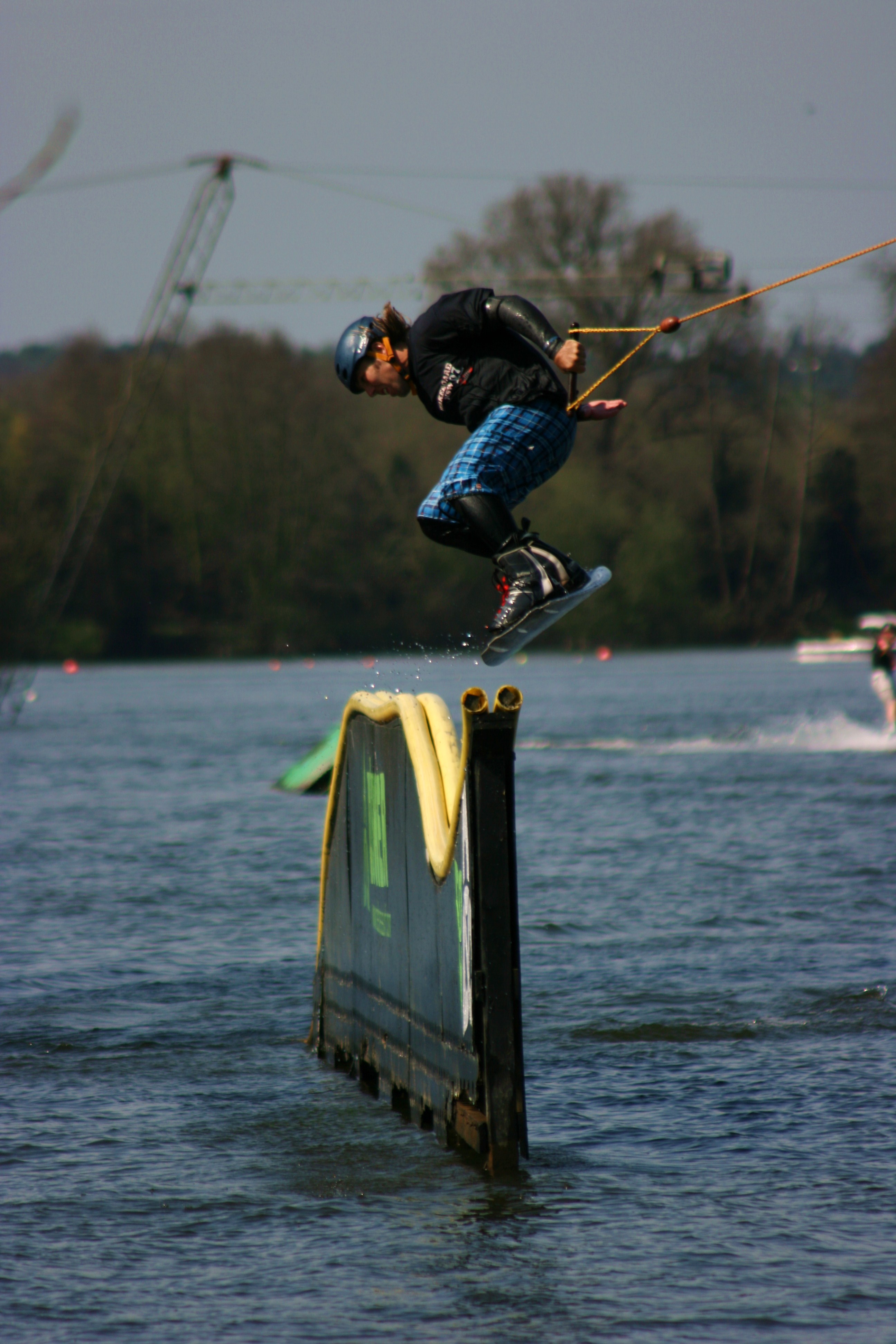 Eban wakeboarding over a rail on a cable course.